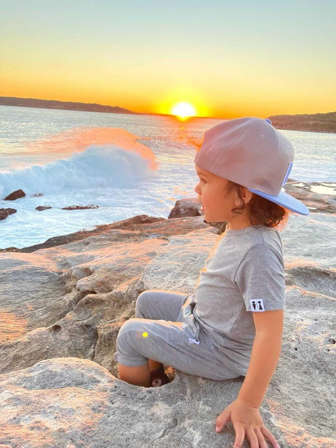 young boy sitting near the beach at sunset
