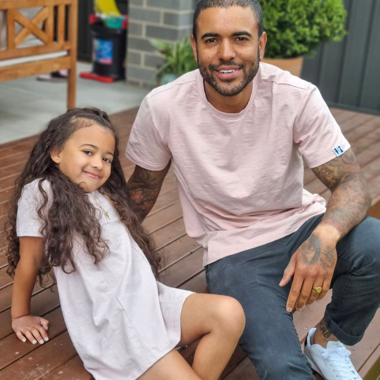 Man and young girl sitting on a wooden bench outdoors