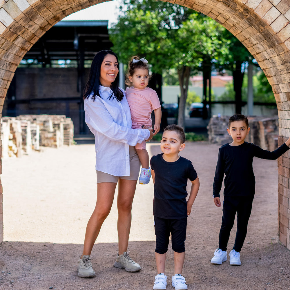 Woman with three children standing under a brick archway